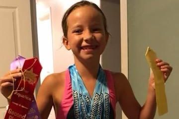 Raelynne Davis shows off her amazing ribbons after competing at a swim meet. She had taken time off from surgery and was back in the swing of things and pushing hard.