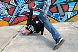 A guy break dances in the street. This form of dance is proposed to be the newest Olympic sport.