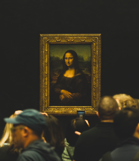 The Mona Lisa is in the center of the view. People walk in the foreground out of focus.