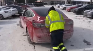 Someone pushes a Tesla Model 3 towards a tow truck at a Chicago Supercharger location. A large number of cars ran out of charge as they waited for a charger.