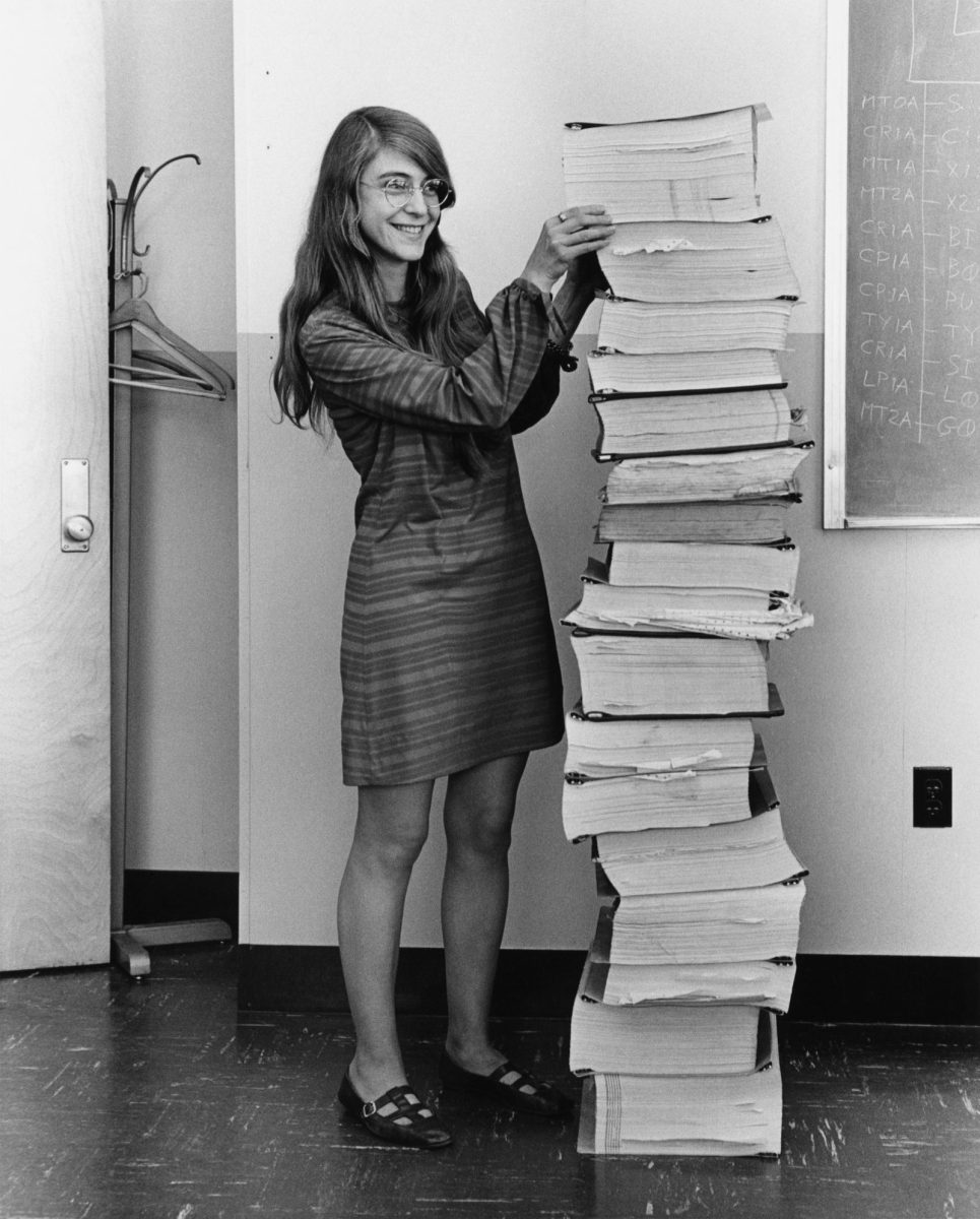 Margret Hamilton stands next to piles of her hand-written code